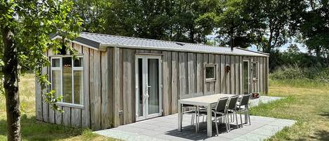 A rustic wooden cabin with a patio and a table with chairs.