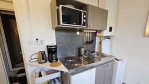 Una kitchenette compacta equipada con microondas, cafetera y lavavajillas Bosch.