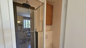 Un baño moderno con cabina de ducha de vidrio, inodoro y mueble de madera.