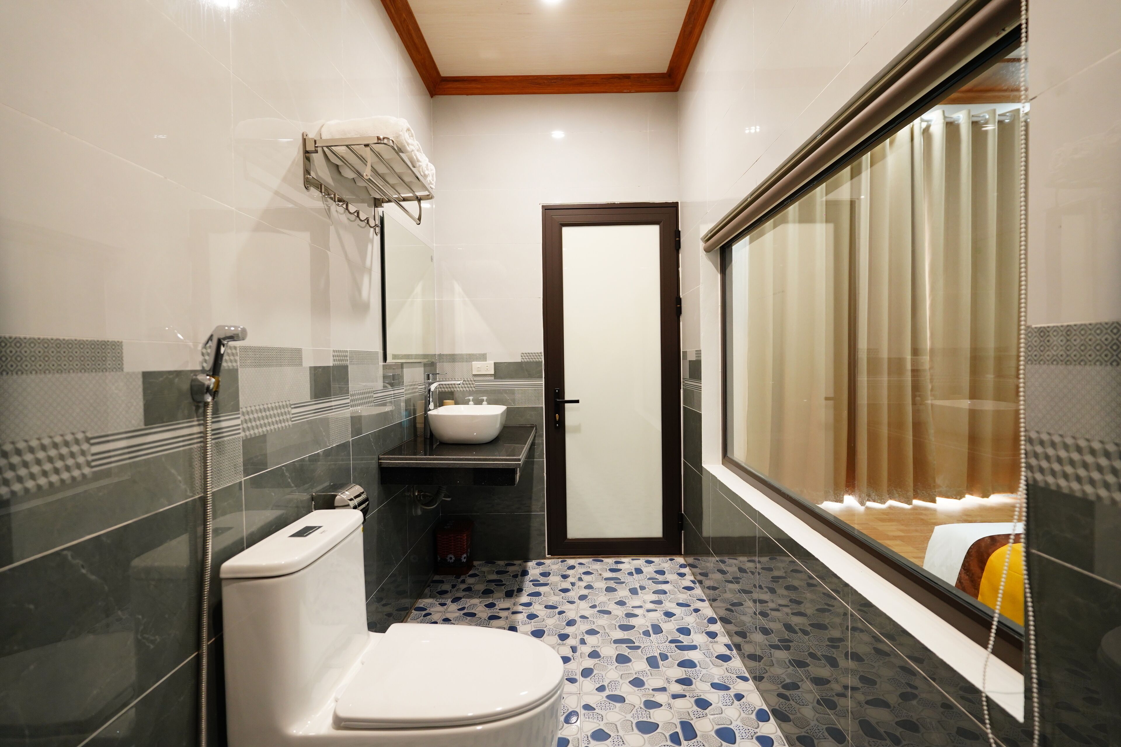 A modern bathroom with a glass shower enclosure, a white toilet, a sink, and a patterned floor.