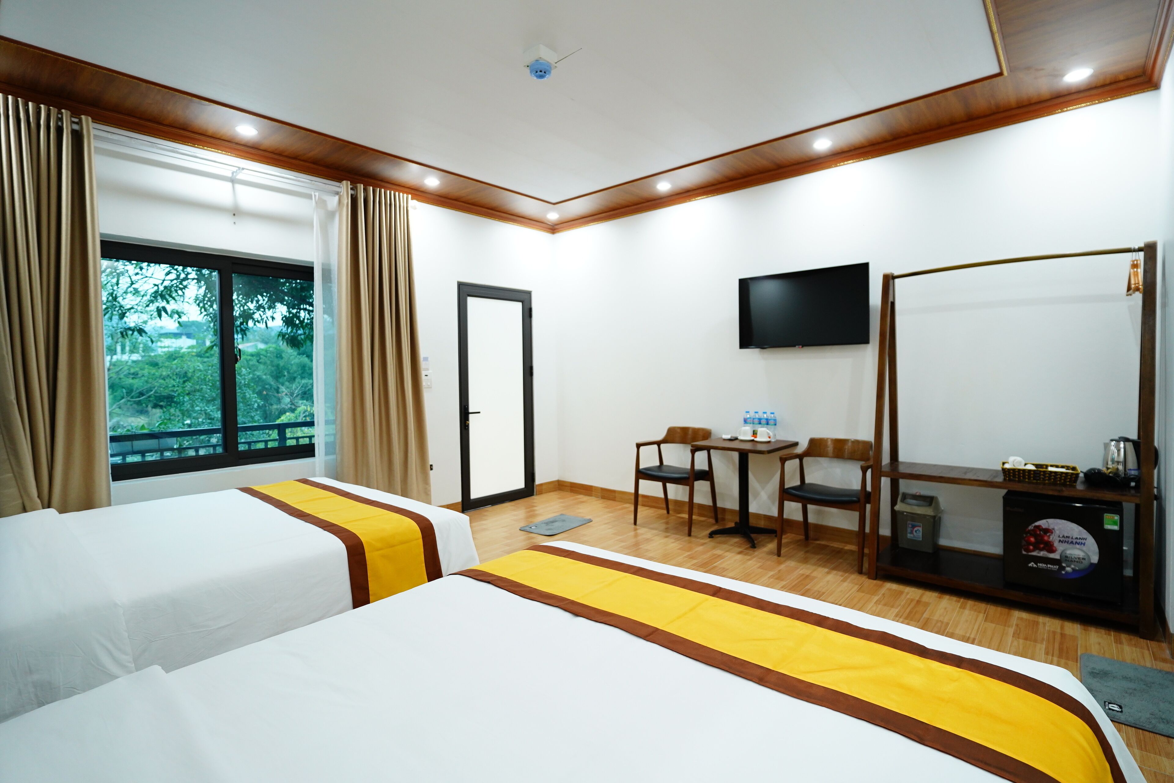 A hotel room with two beds, a desk, a chair, a television, and a window with curtains.