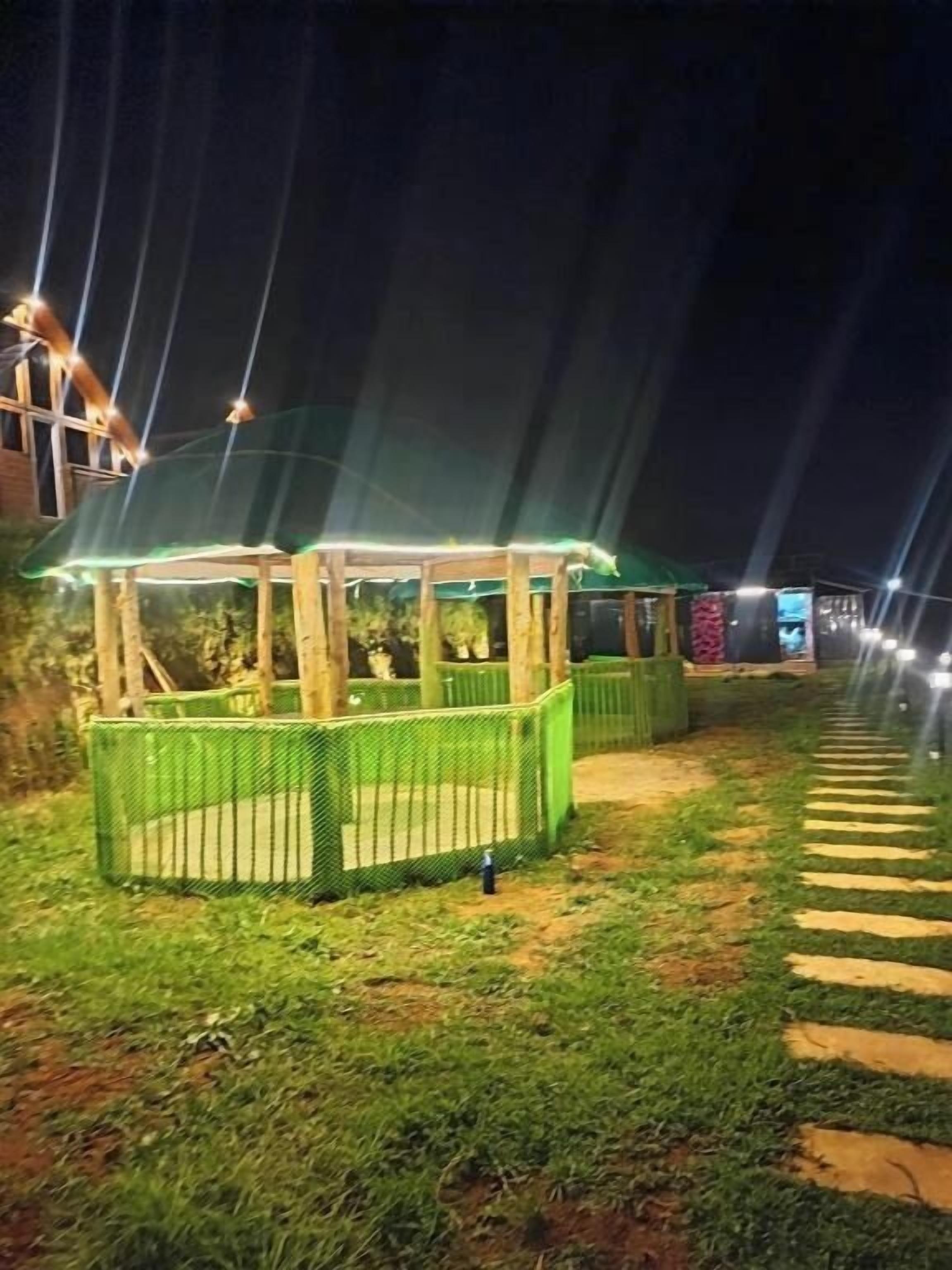 A nighttime outdoor area with a covered seating area and a pathway.