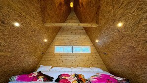 A cozy, wooden interior with a bed, pillows, and a window. - Fairyland Resort (Kodaikanal)