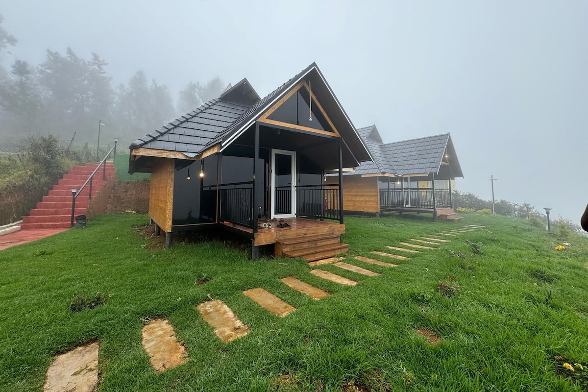 Une cabane avec une façade en bois, une véranda et un escalier menant à l’entrée.