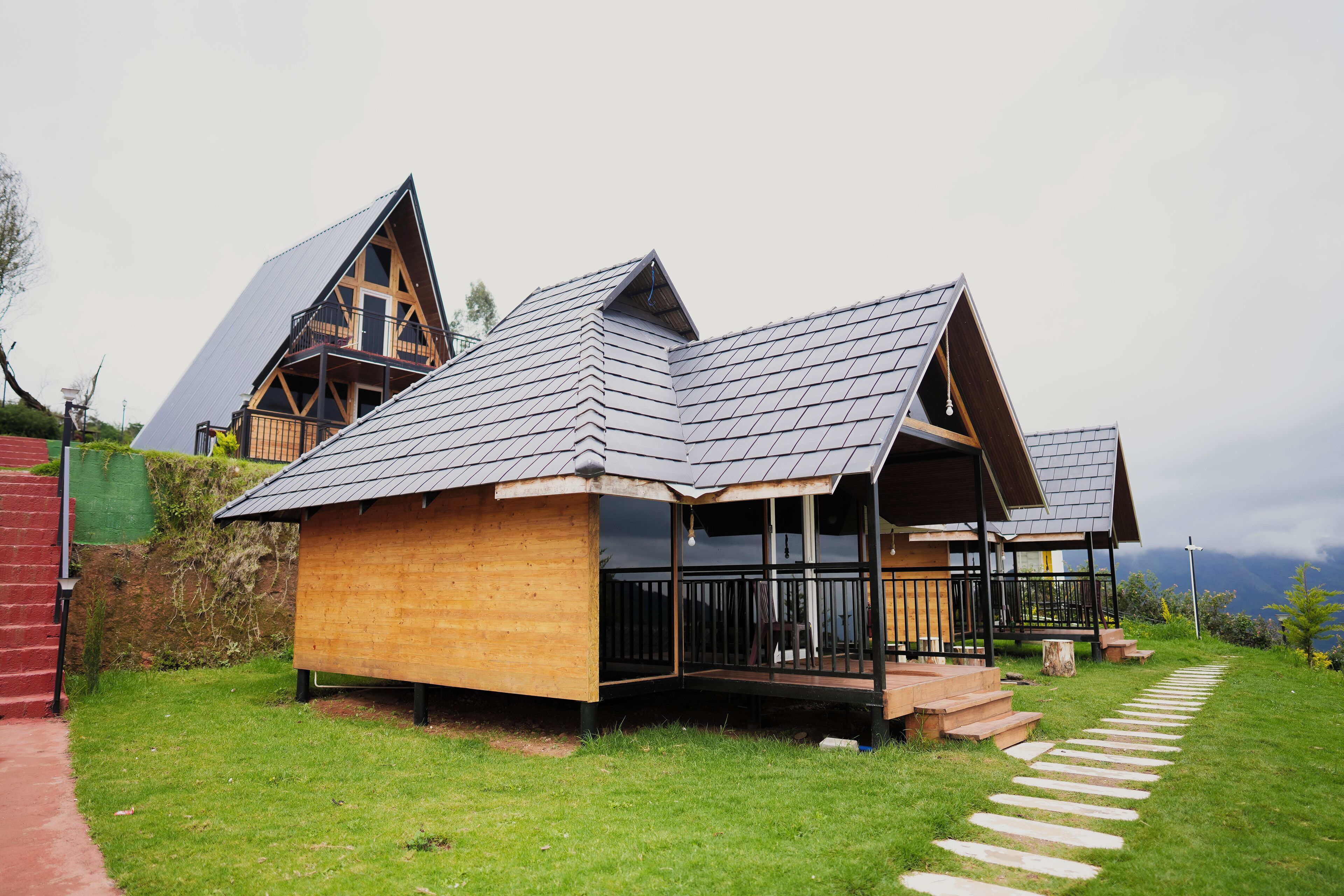 A modern house with a sloped roof, wooden exterior, and a stone pathway leading to the entrance.