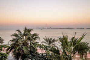 A coastal view with palm trees and a distant building.