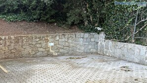 A paved area with a stone wall and a sign indicating a parking space. - Casa Elia - Procchio - Casa Elia - Procchio (Marciana)