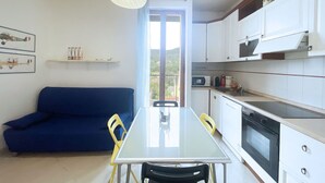 A compact living space with a dining table, a sofa, and a kitchenette. - Casa Elia - Procchio - Casa Elia - Procchio (Marciana)