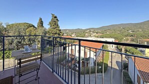A balcony with a table and chairs, overlooking a residential area with houses and trees. - Casa Elia - Procchio - Casa Elia - Procchio (Marciana)