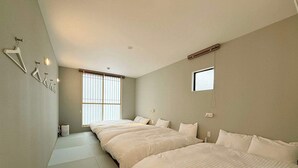 Habitación de hotel con dos camas, un ventanal grande y una mesita de noche pequeña.