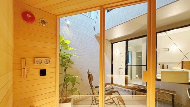 Un baño moderno con cabina de ducha de vidrio, paneles de madera y una planta a la vista.