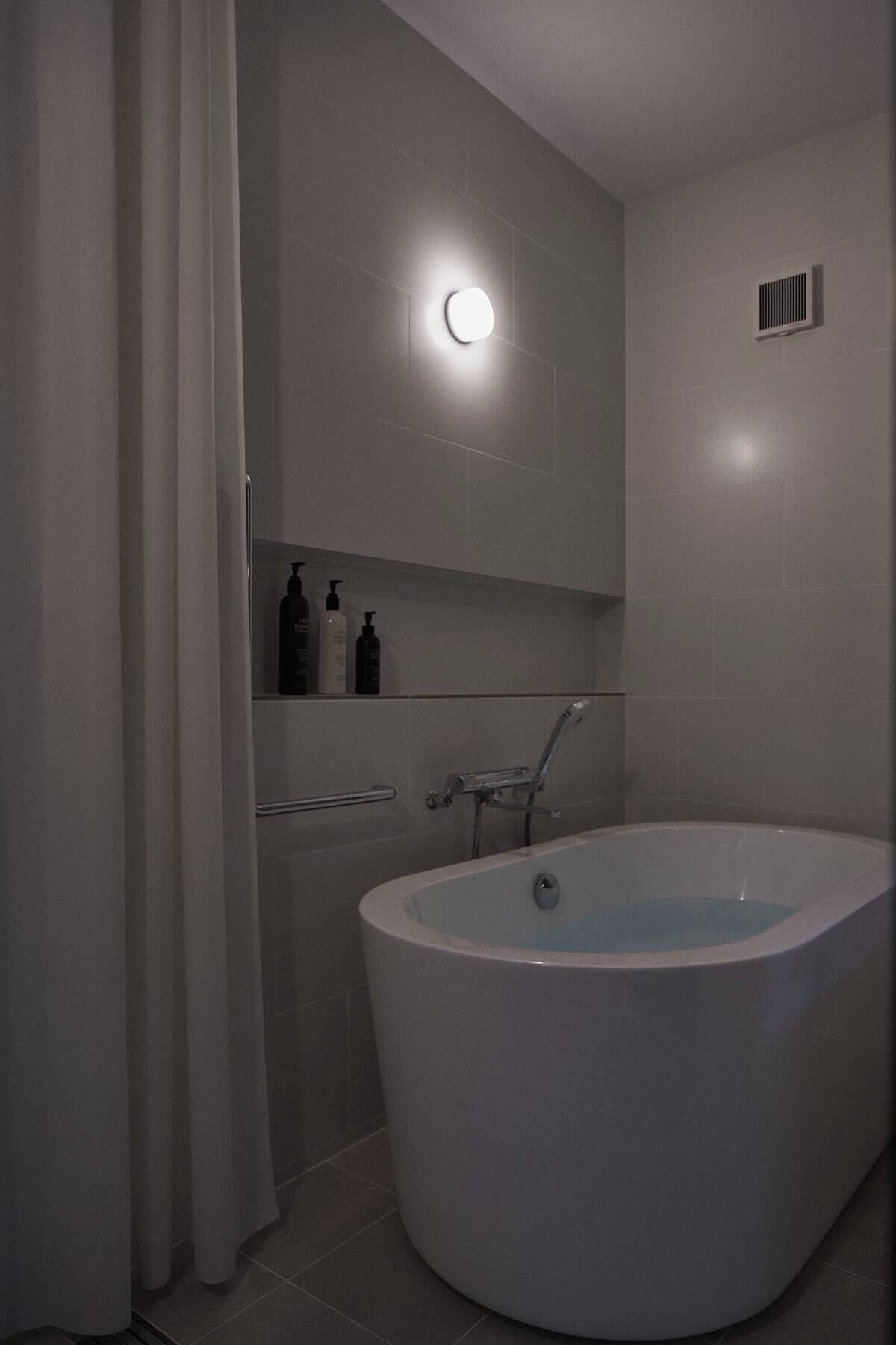 A modern bathroom with a freestanding bathtub, a shower area, and a mirror above the sink.