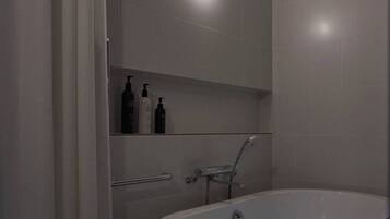 A modern bathroom with a freestanding bathtub, a shower area, and a mirror above the sink.