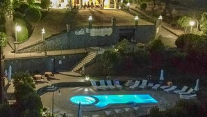 Un grand bâtiment doté d’une piscine, d’un espace extérieur aménagé et d’un escalier menant à l’entrée.