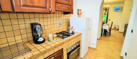 A kitchen with wooden cabinets, a coffee maker, a refrigerator, and a tiled backsplash.
