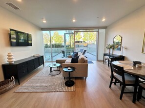 A modern living room with a sofa, coffee table, and dining area. - Hotel-like residence with full kitchen, large patio, pet friendly, free parking (San Diego)