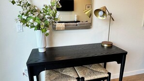 Una scrivania moderna con uno specchio, un vaso con fiori e una lampada.
