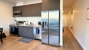 Una cucina moderna con elettrodomestici in acciaio inossidabile, pensili in legno scuro e un tappeto bianco e nero.
