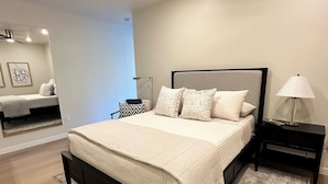 Una camera da letto moderna con un letto grande, una ventola a soffitto, un comodino e uno specchio.