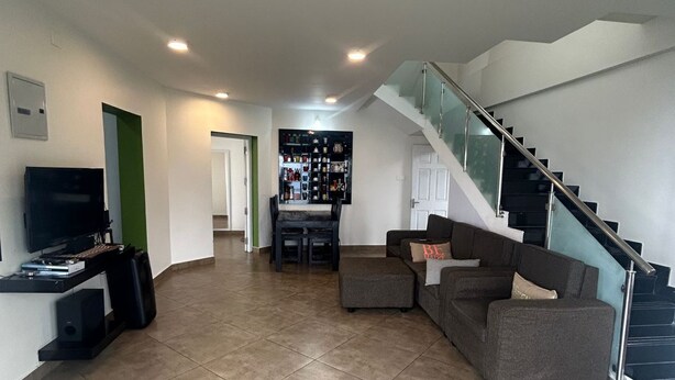 A modern living room with a flat-screen TV, a sofa, and a staircase. - S ELLA Residency (Kotagiri)