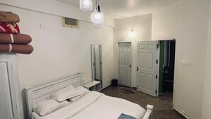 A bedroom with a bed, bedside tables, a wardrobe, and a mirror. - S ELLA Residency (Kotagiri)