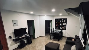 A modern living room with a flat-screen TV, a black sofa set, a coffee table, and a bookshelf. - S ELLA Residency (Kotagiri)