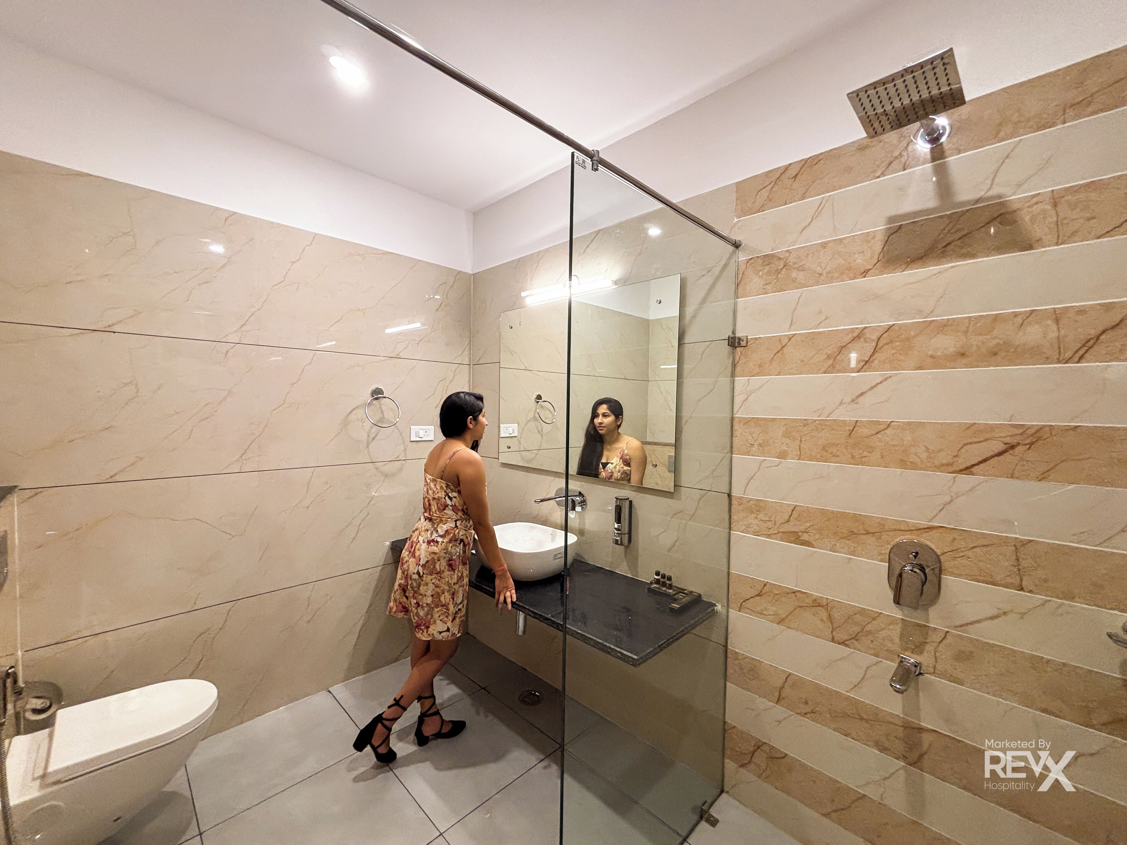 A modern bathroom with a glass shower enclosure, a white toilet, and a marble-tiled wall.