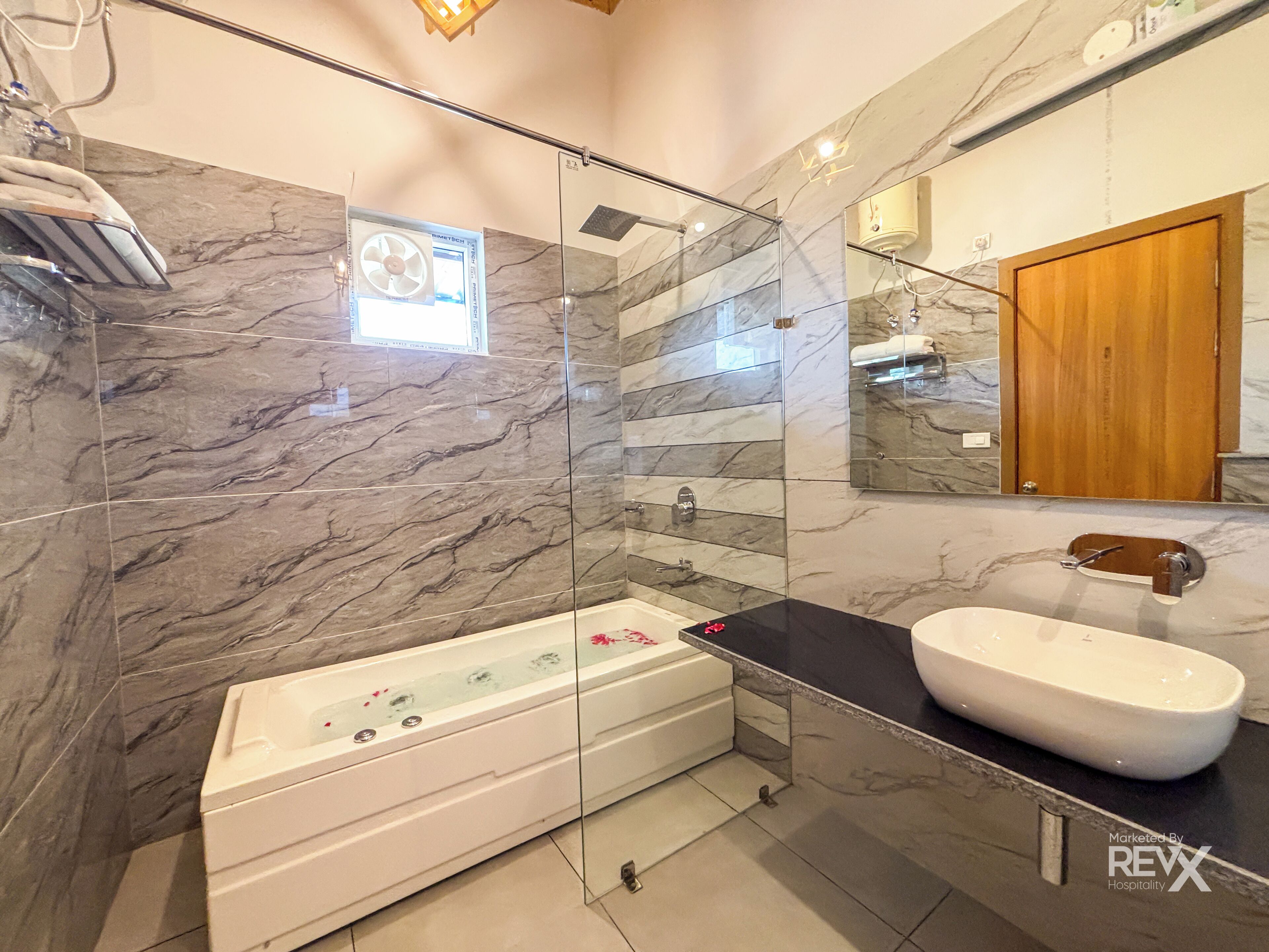 A modern bathroom with a glass-enclosed shower, a white bathtub, and a black countertop sink.