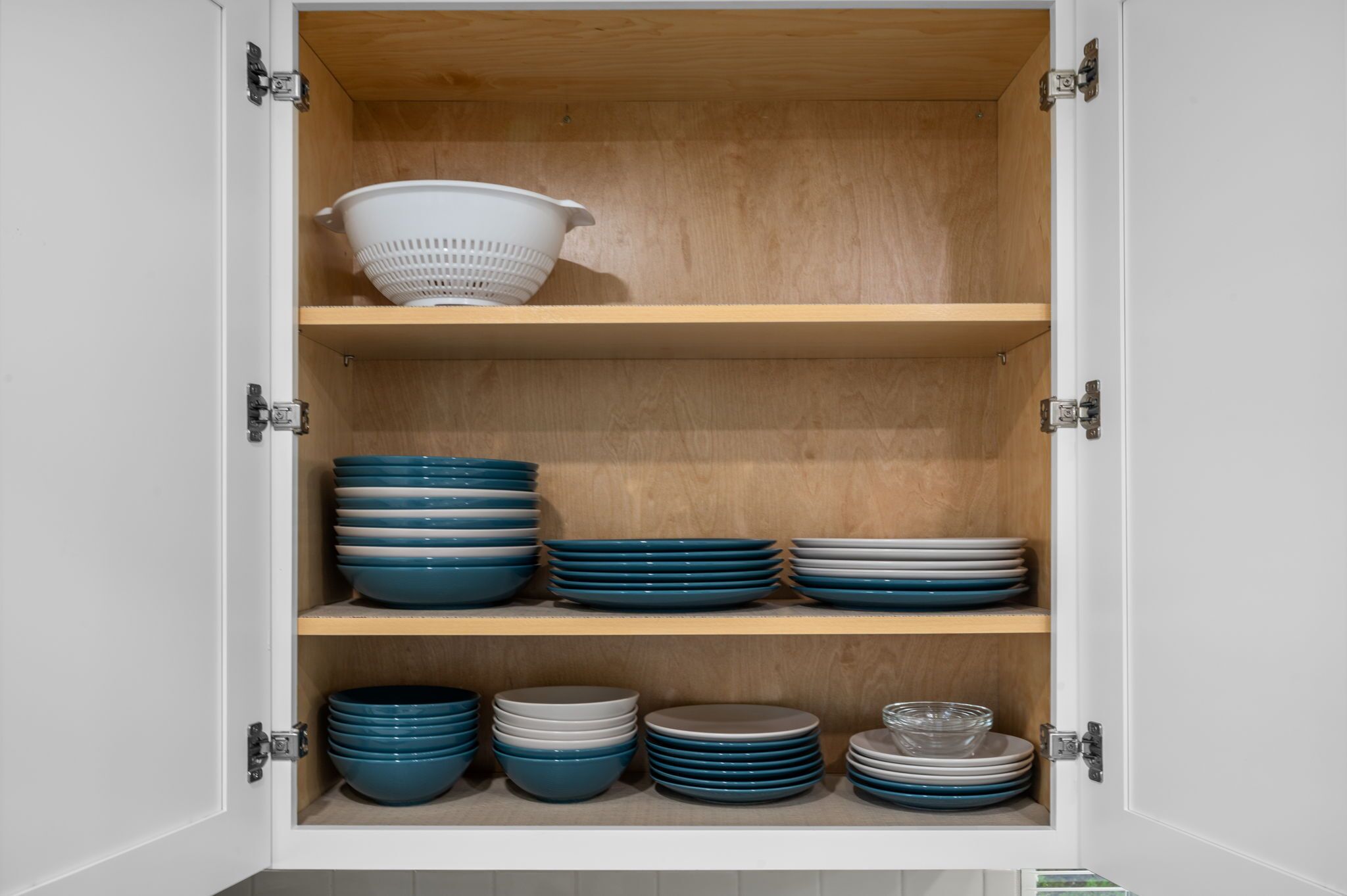 A cabinet with three shelves, each holding stacks of blue and white plates.