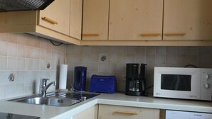 Una cucina con mobili in legno, un lavandino, una macchina da caffè, un tostapane e un forno a microonde.