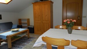 A cozy living room with a sofa, a dining table with chairs, a wooden cabinet, and a skylight. - Apartment (03) with balcony and extra kitchen (Reit im Winkl)