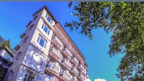 A multi-story building with balconies, signage for 'Chichoga Holiday Inn', and a clear blue sky. - Chichoga Holiday Inn Manali (Manali)