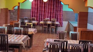 A restaurant with multiple tables and chairs, a stage with curtains, and hanging spherical lights. - Chichoga Holiday Inn Manali (Manali)