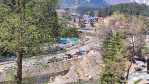 A mountainous town with a parking lot and buildings in the foreground. - Chichoga Holiday Inn Manali (Manali)
