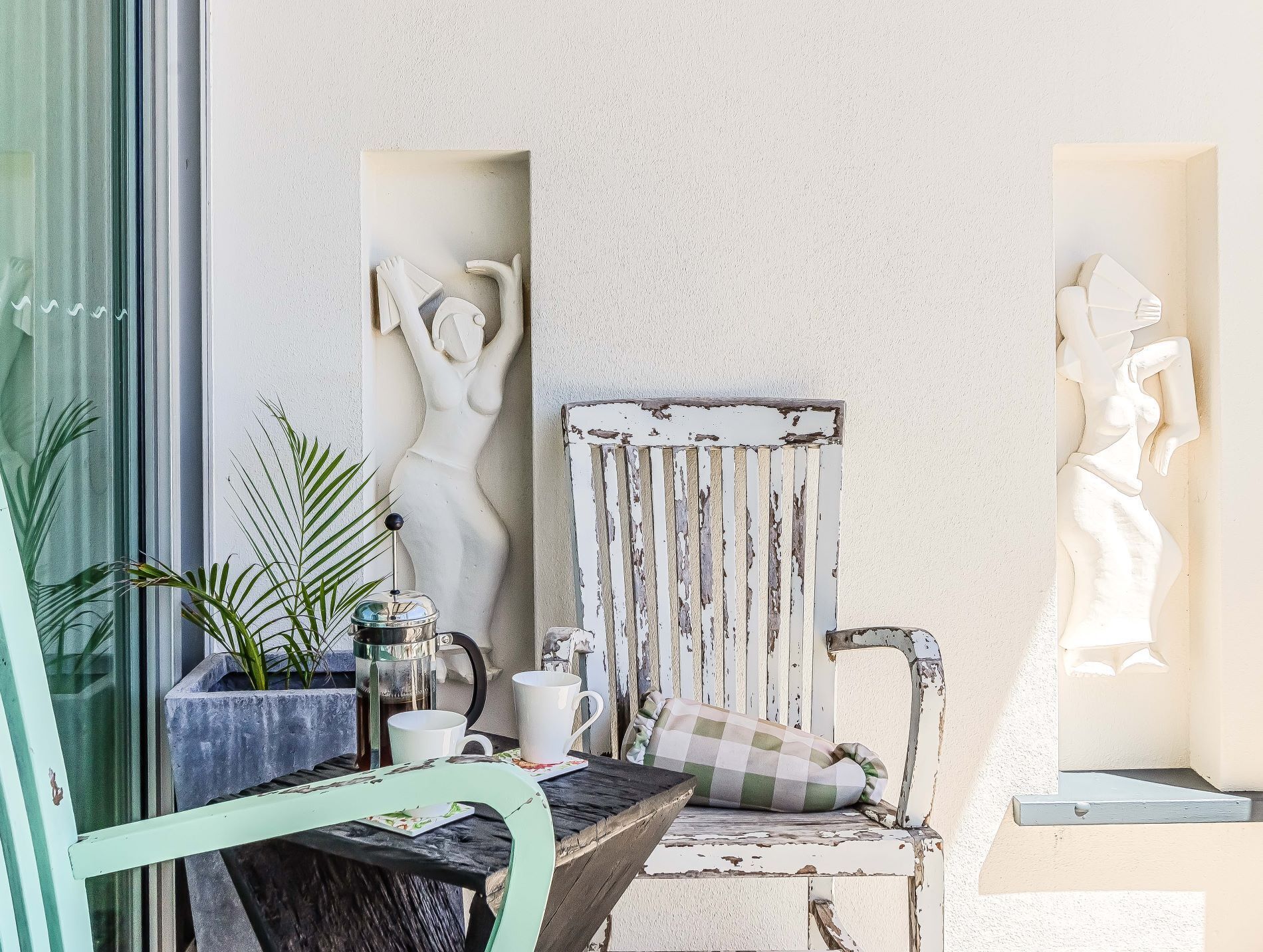 A rustic outdoor seating area with a weathered wooden chair, a small table, and a potted plant.