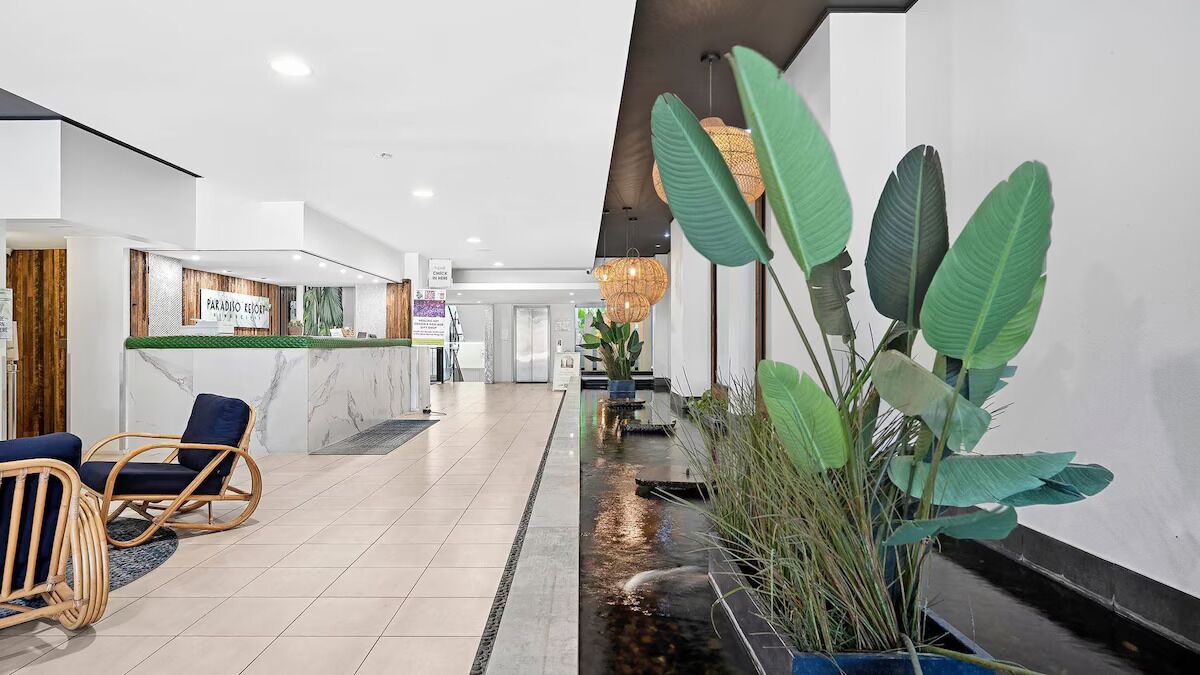 A modern reception area with a marble reception desk, wicker chairs, and a water feature.