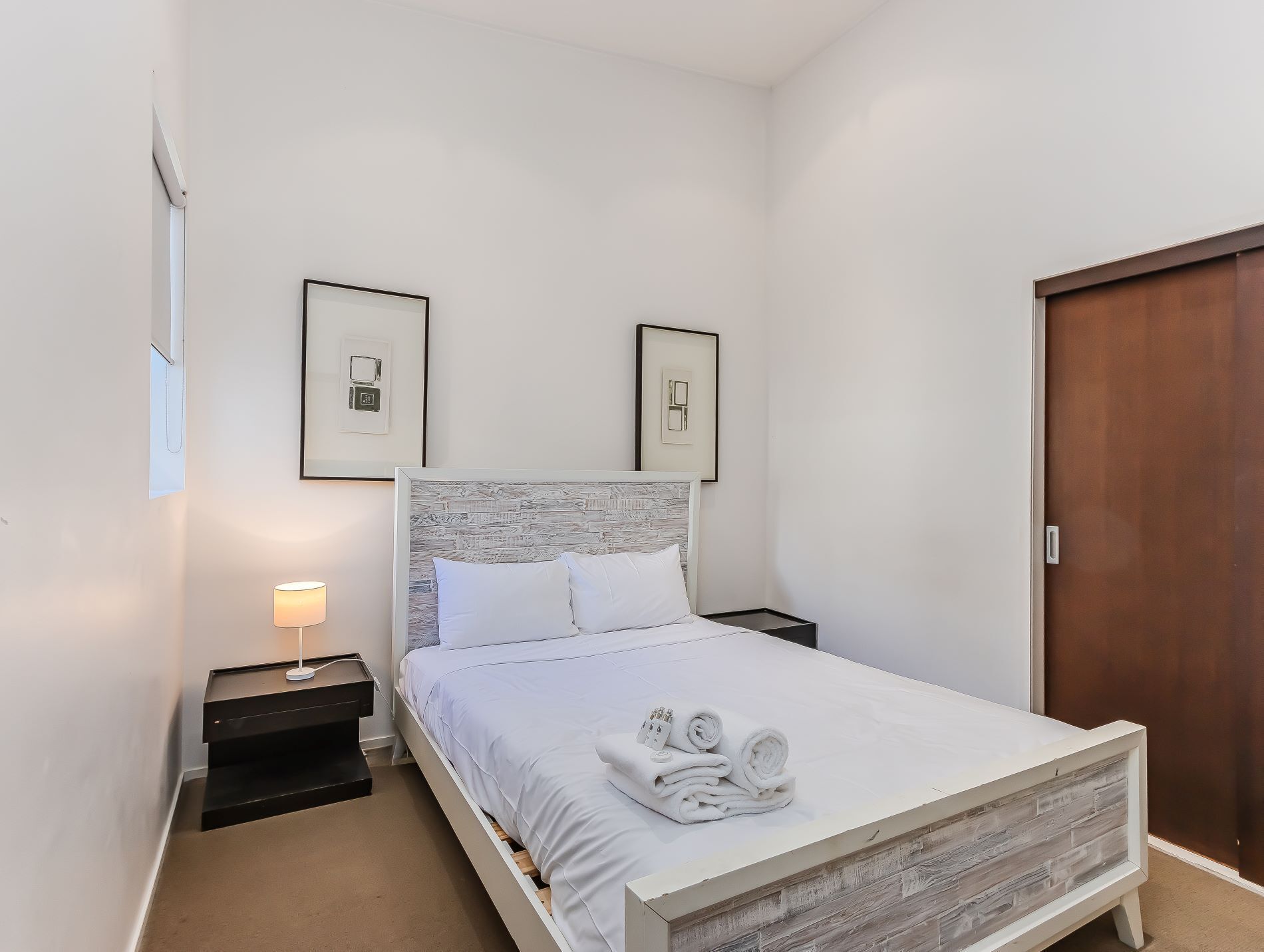 Un dormitorio ordenado con cama, dos mesitas de noche y un armario de madera.