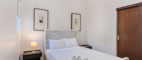 Un dormitorio ordenado con cama, dos mesitas de noche y un armario de madera.