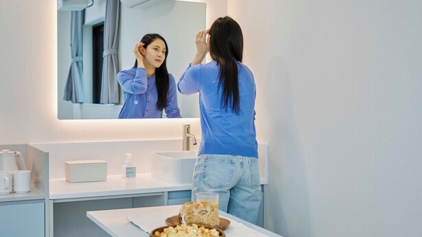 A modern bathroom with a large mirror, a sink, and a table with a bowl of popcorn and a glass of water. - Anook Air Hotel Gaebong (Seoul)
