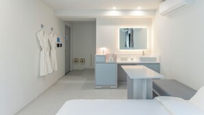 A modern hotel room with a bed, a small desk, a vanity with a mirror, a mini-fridge, and a wall-mounted air conditioner. - Anook Air Hotel Gaebong (Seoul)
