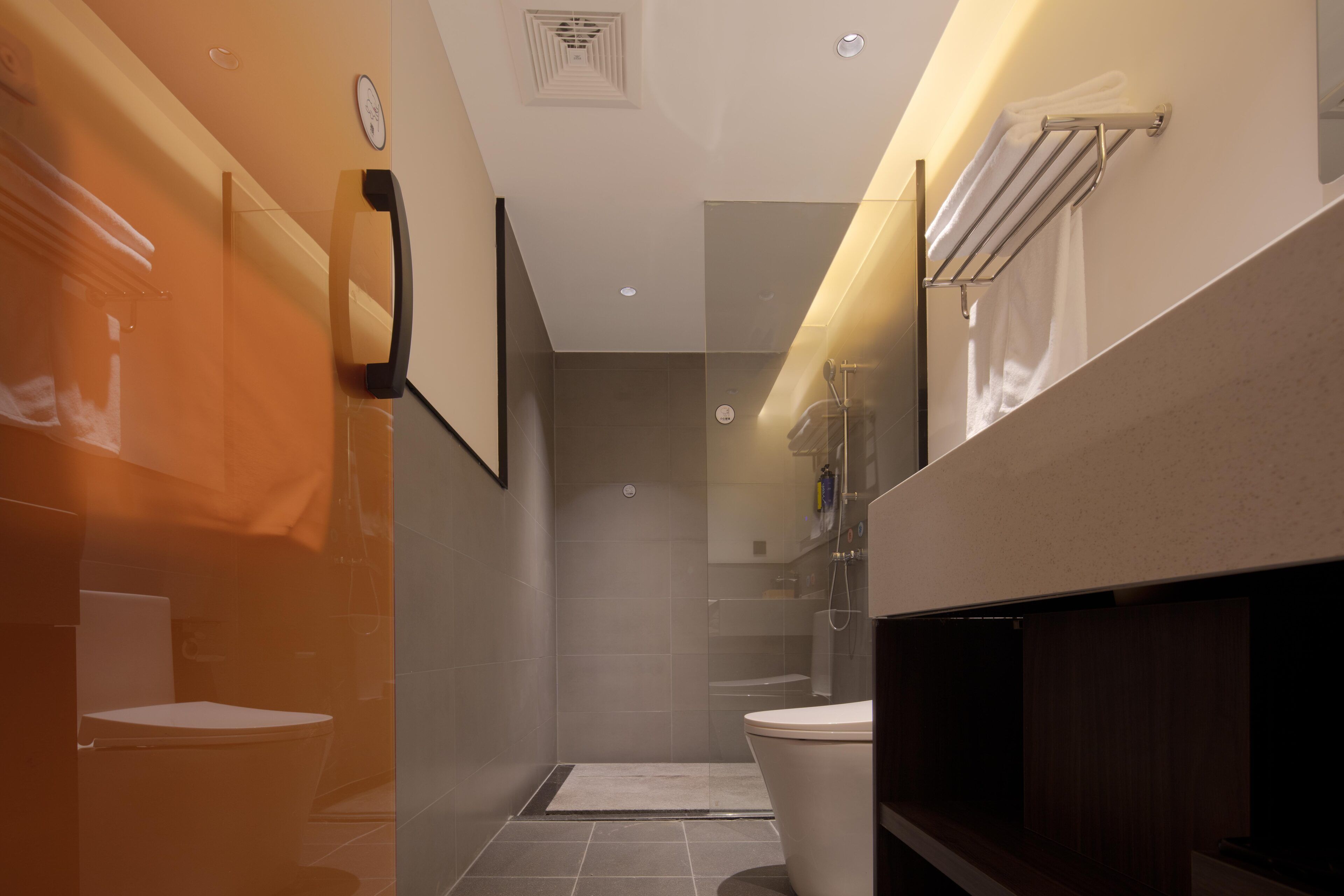 Un baño moderno con cabina de ducha de vidrio, inodoro y tocador con espejo.