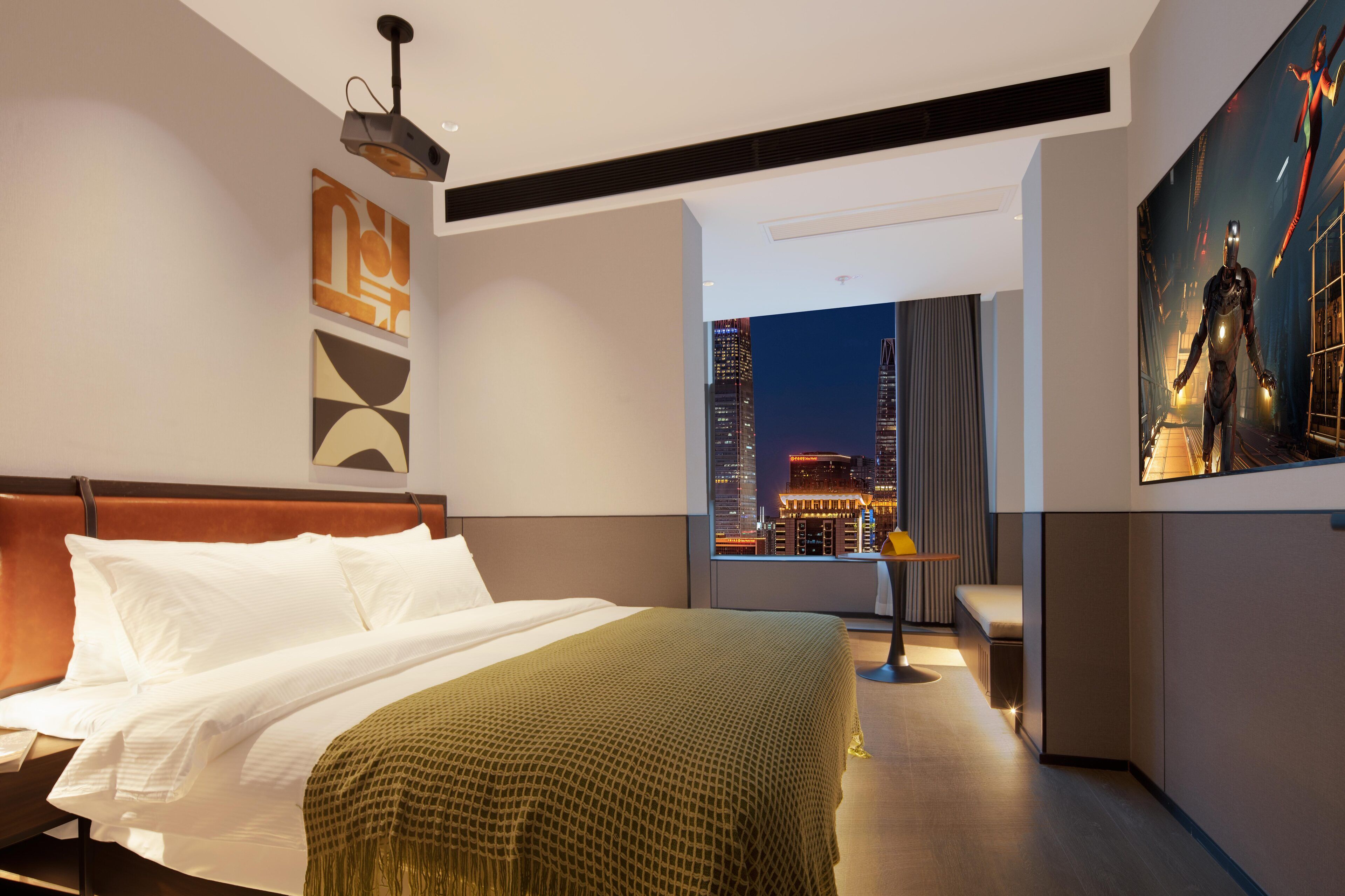 Una habitación de hotel moderna con una cama grande, vistas a la ciudad y un póster grande en la pared.
