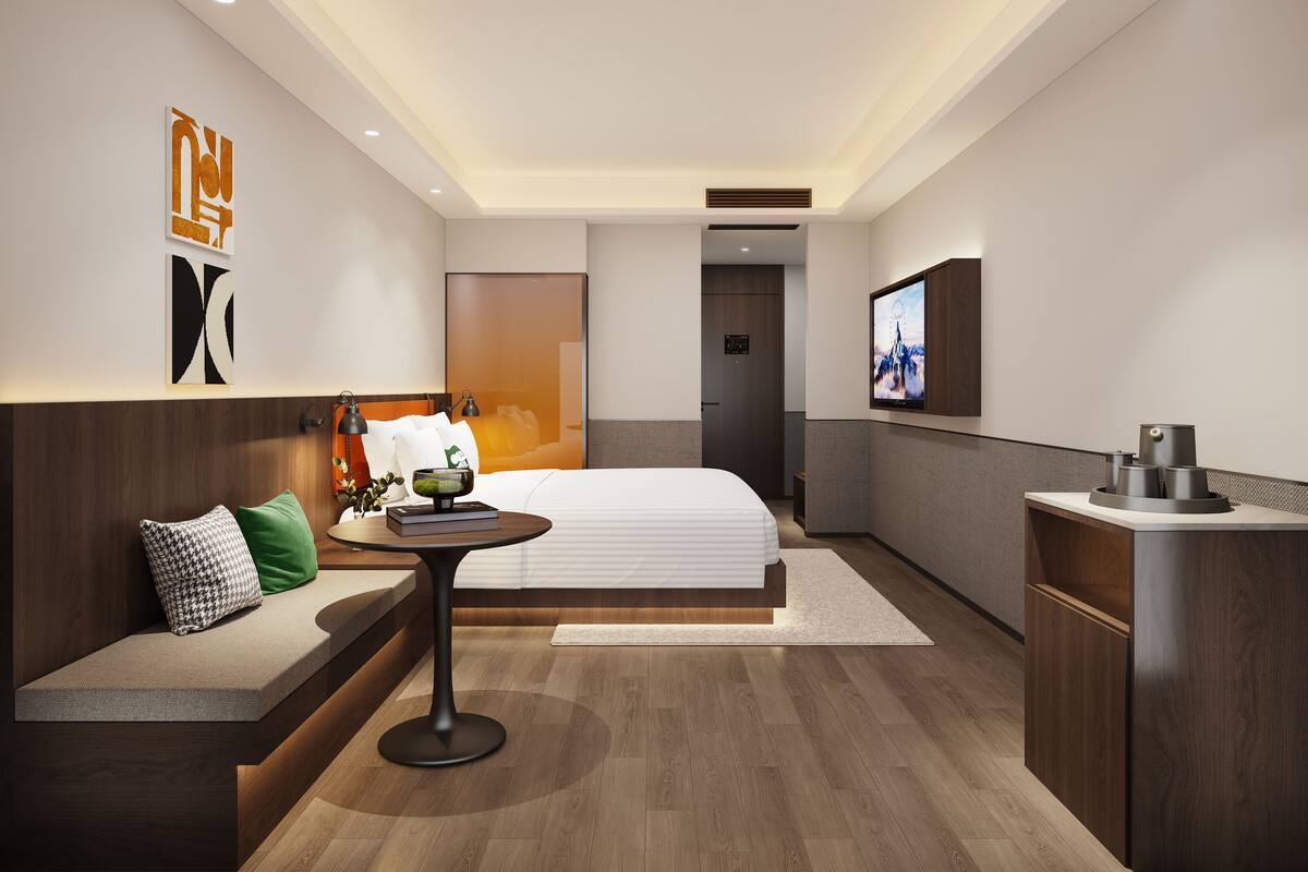 Quarto de hotel moderno com uma cama, área de estar com mesa, televisão e minibar.