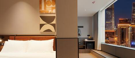 Ein modernes Hotelzimmer mit einem großen Bett, Stadtblick und zeitgemäßem Design.