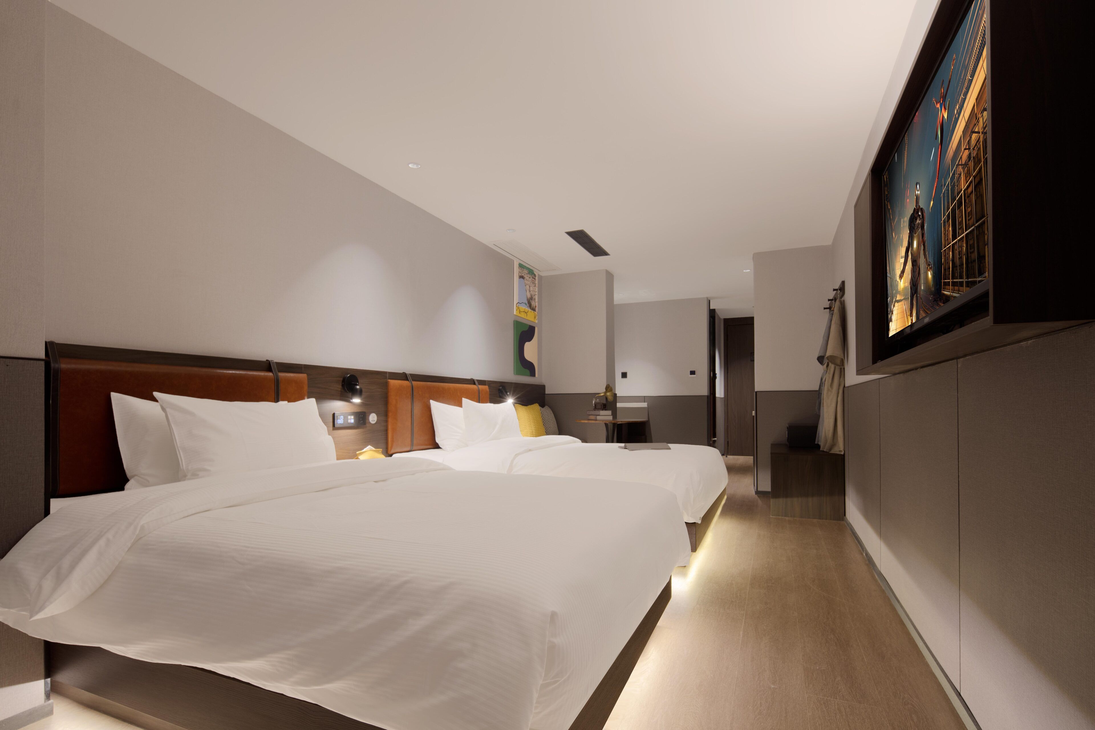 Une chambre d’hôtel avec deux lits, une tête de lit en bois, une table de chevet et un tableau au mur.