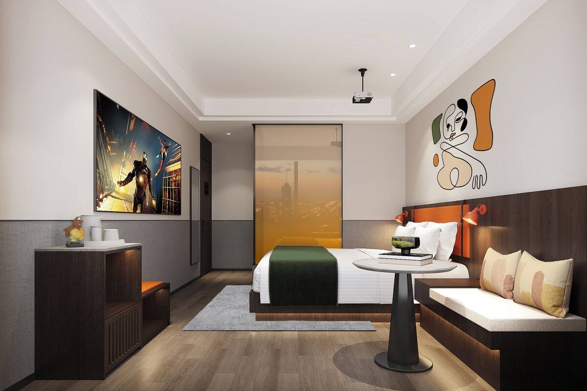 Quarto de hotel moderno com cama, sofá, escrivaninha e uma grande pintura na parede.