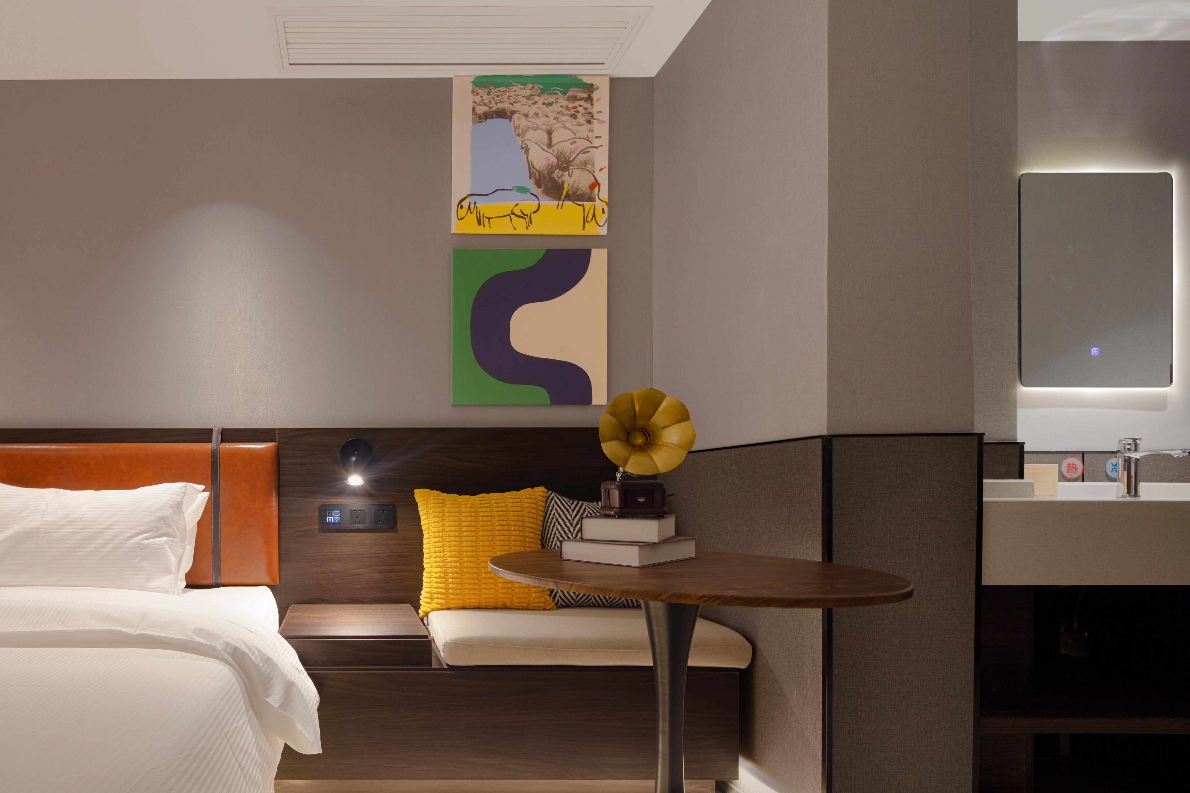 Una habitación de hotel moderna con una cama, un sofá, una mesita y un televisor de pared.