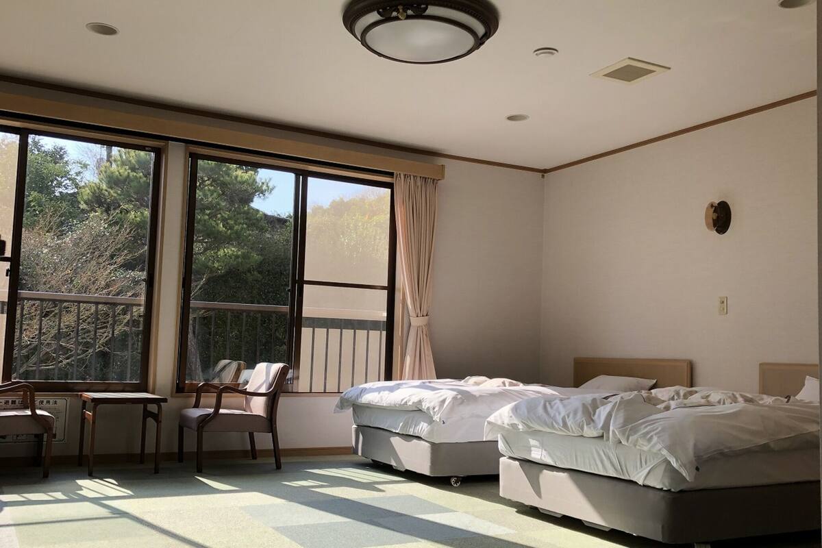A bedroom with two beds, a desk, and chairs.