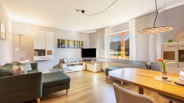A modern living room with a sofa, a dining table, and a TV. - "Klein und Fein" Holiday Apartment – Your Getaway at Lake Edersee (Edertal)
