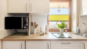 A modern kitchen with a microwave, a sink, and a window with blinds. - "Klein und Fein" Holiday Apartment – Your Getaway at Lake Edersee (Edertal)